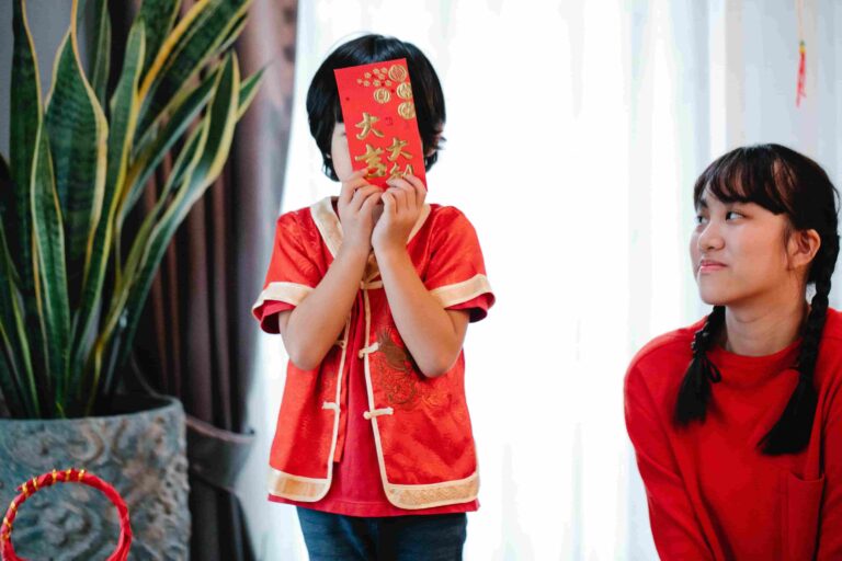 Zdjęcie przedstawia nie do rozpoznania chłopca trzymającego kopertę obok swojej azjatyckiej siostry podczas świątecznego wydarzenia.