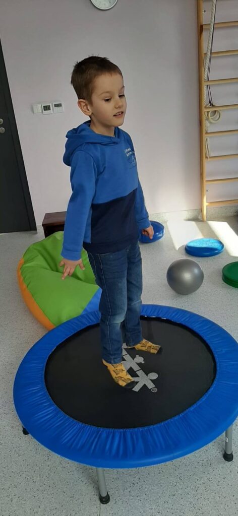 Chłopczyk skaczący na trampolinie w pomieszczeniu.